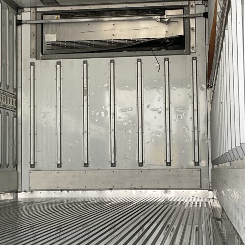 Interior of an empty refrigerated trailer with ribbed metal floor and metal wall panels.